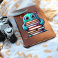 "Elegant Leather Journal – Cute Monster with Stack of Books Design"
